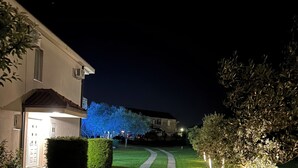 Eine beleuchtete Wohnstraße bei Nacht mit Häusern.