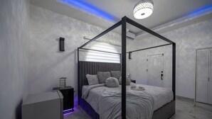 Ein modernes Schlafzimmer mit einem Himmelbett, einem Nachttisch und einer Deckenleuchte.