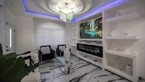 Ein modernes Wohnzimmer mit Fernseher, weißen Regalen und einem Marmorboden.