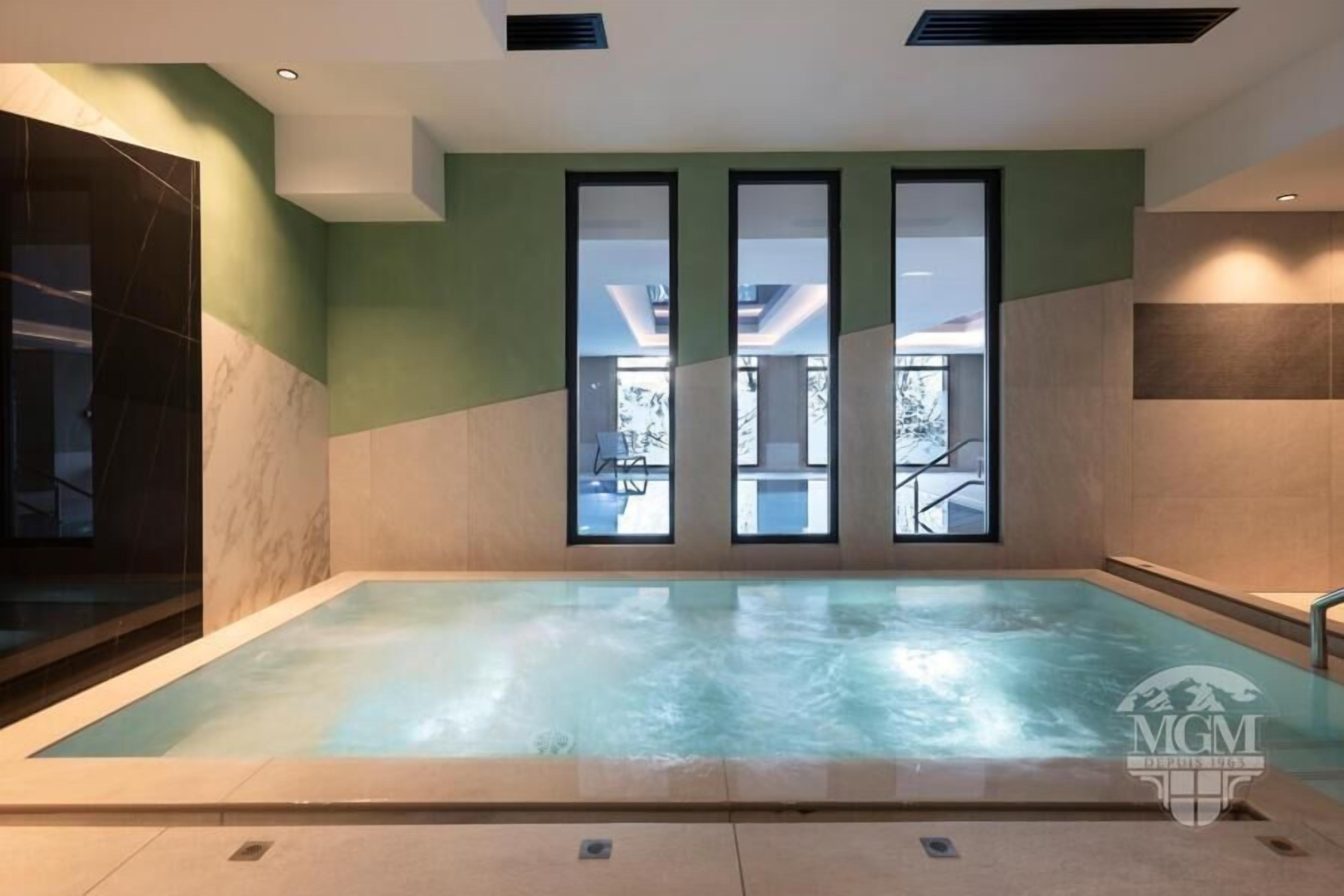 A swimming pool with a view of a building through large windows.