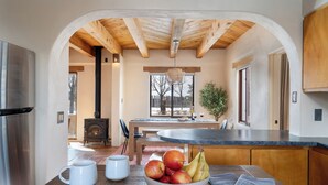 A modern kitchen with a central island, wooden beams, a stove, and a dining area with a view. - Oasis Escondido / Stunning Views / Spa / Firepit / Location / Private! (El Prado)