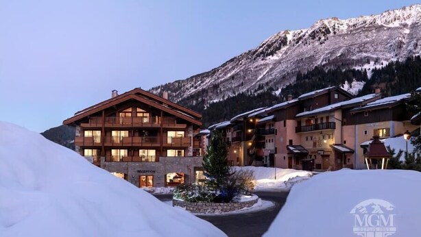 A multi-story hotel with a wooden facade, a stone foundation, and balconies. - Wifi, view village, fitness, swimming pool, sauna, hammam, balcony, tv, ski locker, 65m², Valmorel (Valmorel)