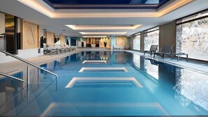 Ein moderner, überdachter Innenpool mit klarem Wasser und einer versenkten Sitzgelegenheit.