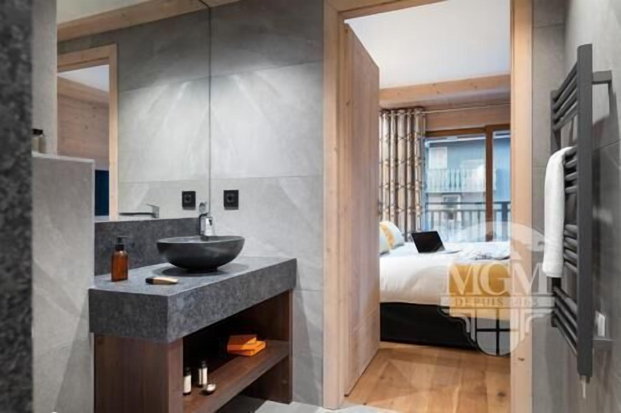 Une salle de bain moderne avec un grand miroir, un lavabo sur colonne et un meuble-lavabo en bois.