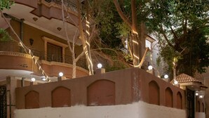 A courtyard with a low wall, trees, and a building with balconies. - Pyramids Lodge (Giza)