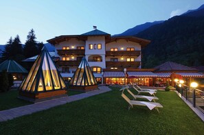 A hotel with multiple balconies, outdoor seating, and a mountain backdrop.