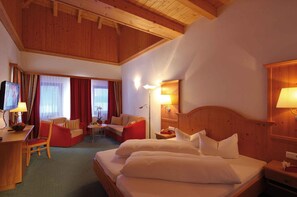 A hotel room with a bed, a desk, a chair, a sofa, and a television.