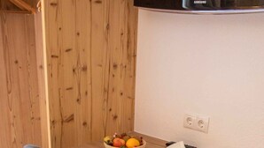 A wooden desk with a bowl of fruit, an open book, and a remote control. - Holiday apartment with wellness area (Ötz im Ötztal)