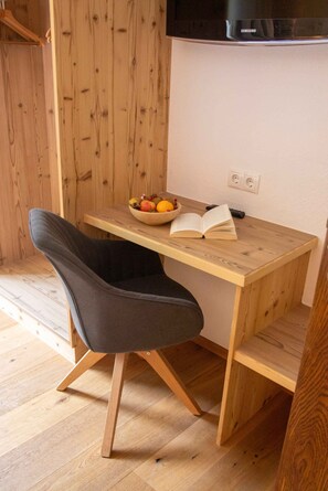 A wooden desk with a bowl of fruit, an open book, and a remote control. - Holiday apartment with wellness area (Ötz im Ötztal)