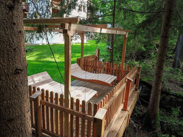 A wooden deck with a wooden fence and a swing set.