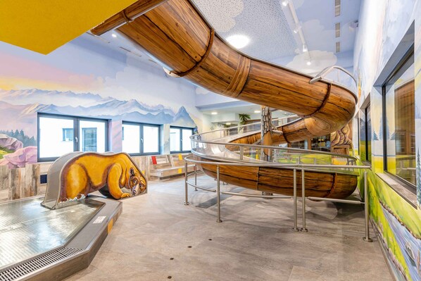 A modern interior with a wooden boat structure, a large mural of mountains, and a dog sculpture.