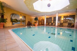 A large indoor swimming pool with tiled walls and a mural of a landscape.