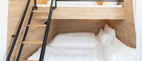 Un lit superposé avec une échelle en bois et du linge de lit blanc.