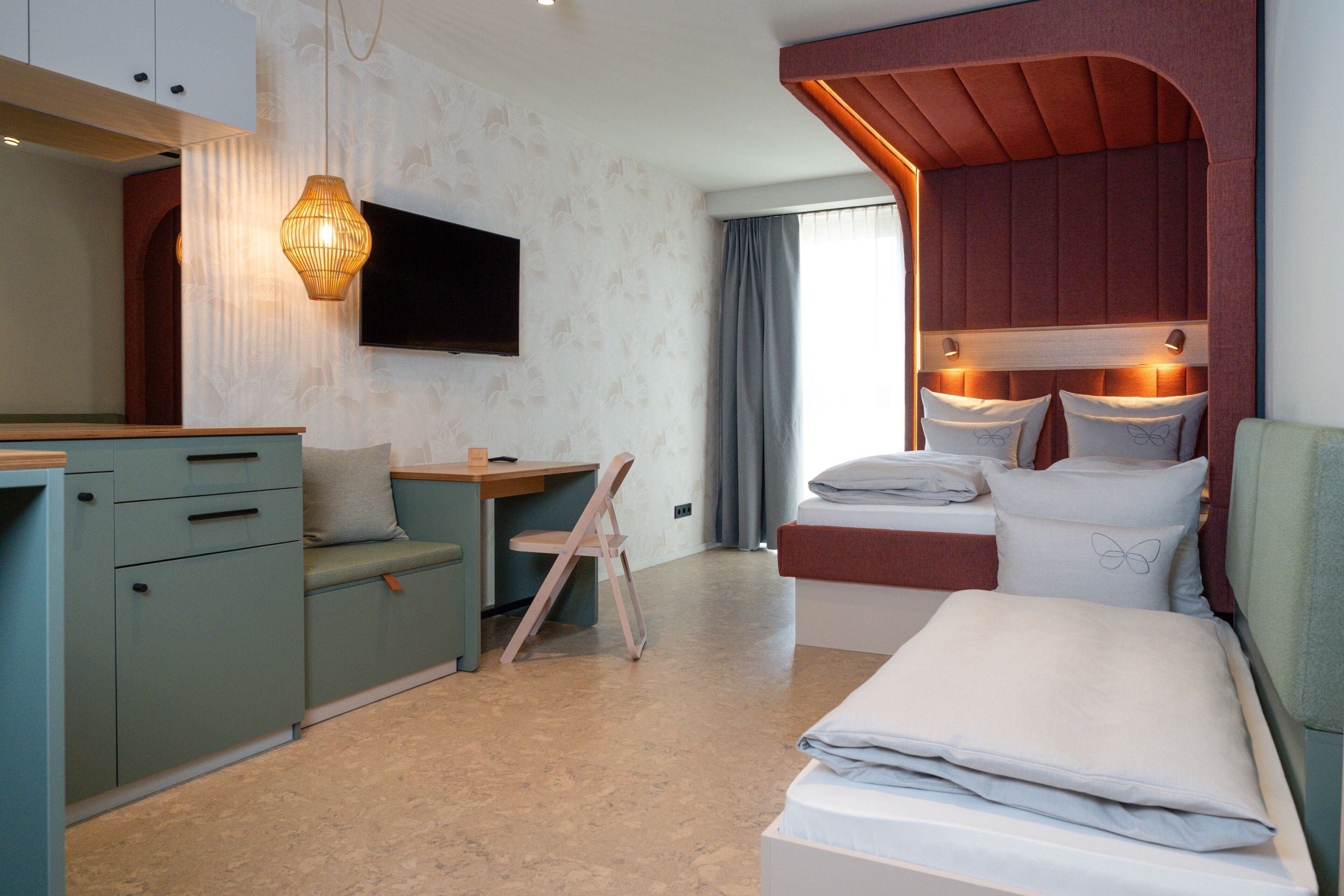 Een hotelkamer met een bed, een bureau, een stoel, een televisie en een raam met gordijnen.