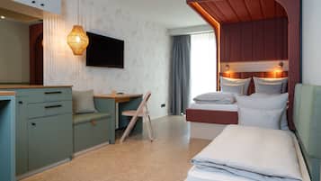 A hotel room with a bed, a desk, a chair, a television, and a window with curtains.