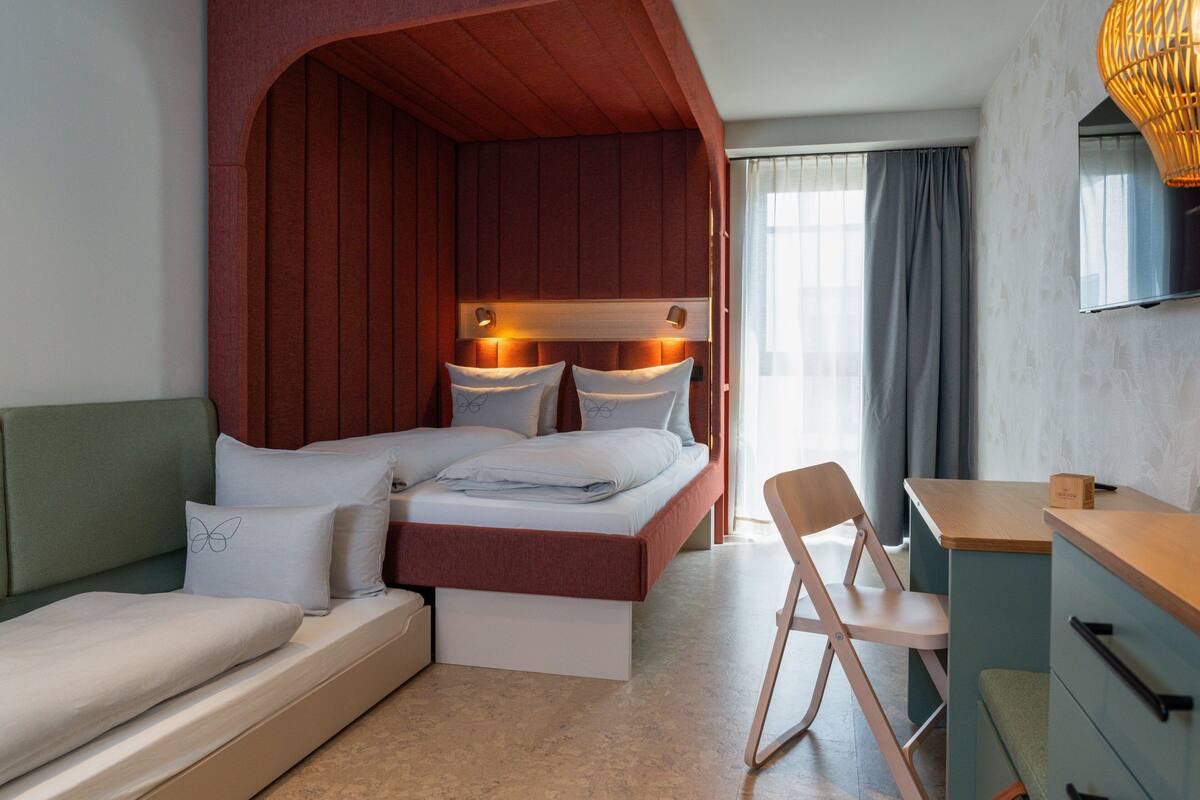 A bedroom with a bed, a desk, and a chair.