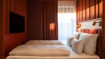 Une chambre avec un lit, des rideaux, une télévision et une tête de lit dotée de lampes.