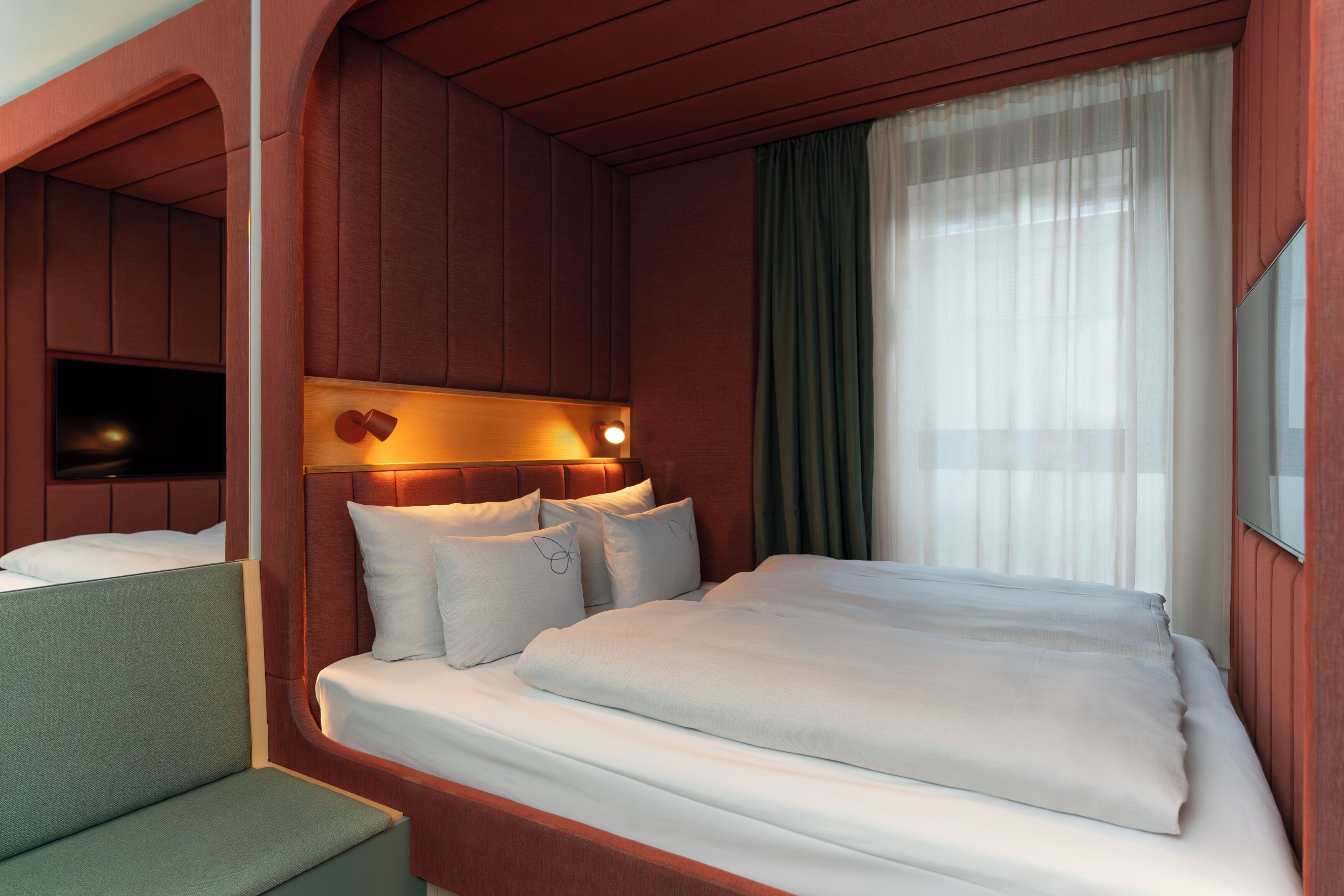 A hotel room with a bed, a seating area, a television, and a window with curtains.