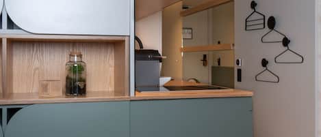 Una cocina con encimera de madera, un tarro de vidrio con plantas y una lámpara colgante.