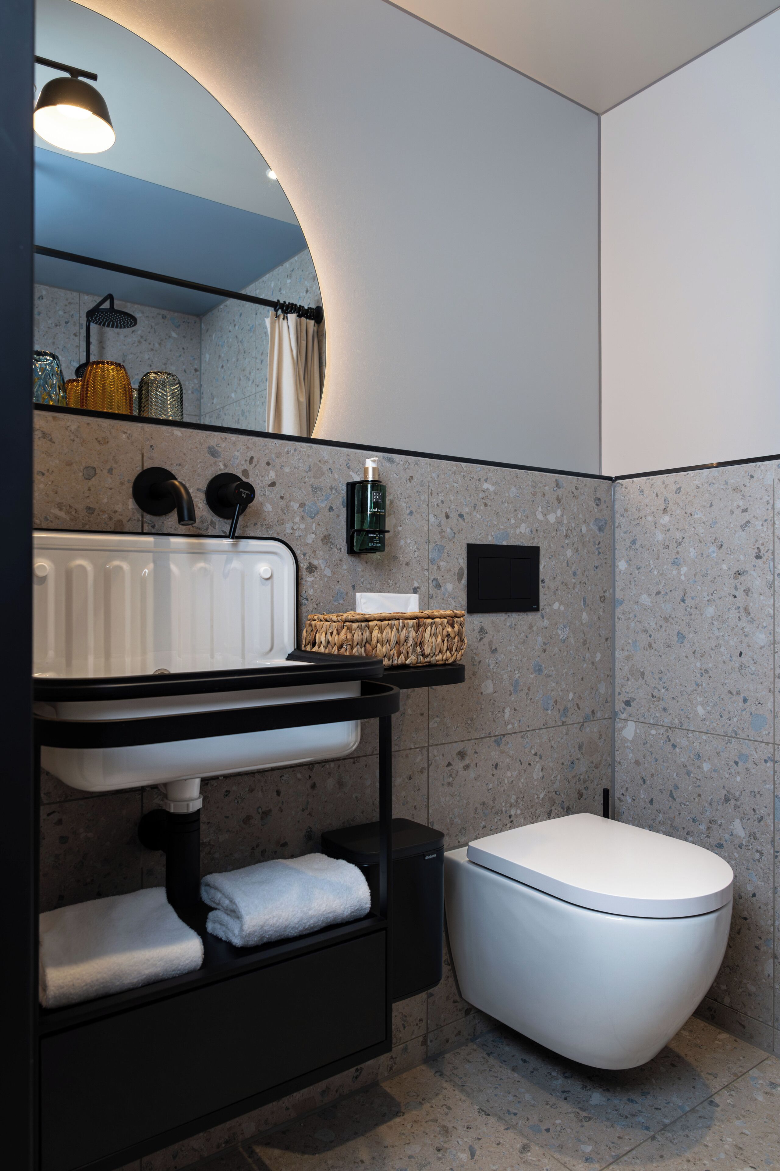 A modern bathroom with a white sink, black faucet, and a white toilet.