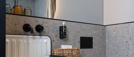 A modern bathroom with a white sink, black faucet, and a white toilet.