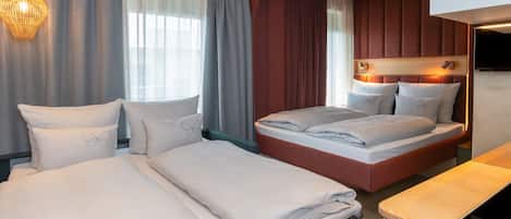 A hotel room with two beds, a wooden headboard, a flat-screen TV, and a large window with curtains.