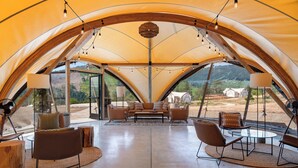 A spacious tent with a high ceiling, furnished with leather chairs, a sofa, and a coffee table.