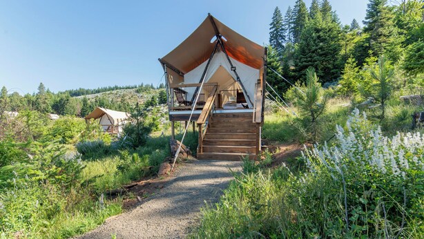 A rustic cabin with a wooden deck and a large tent-like structure.