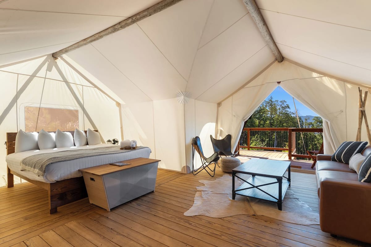 Un hébergement sous tente comprenant un lit, une petite table, un canapé et une chaise.
