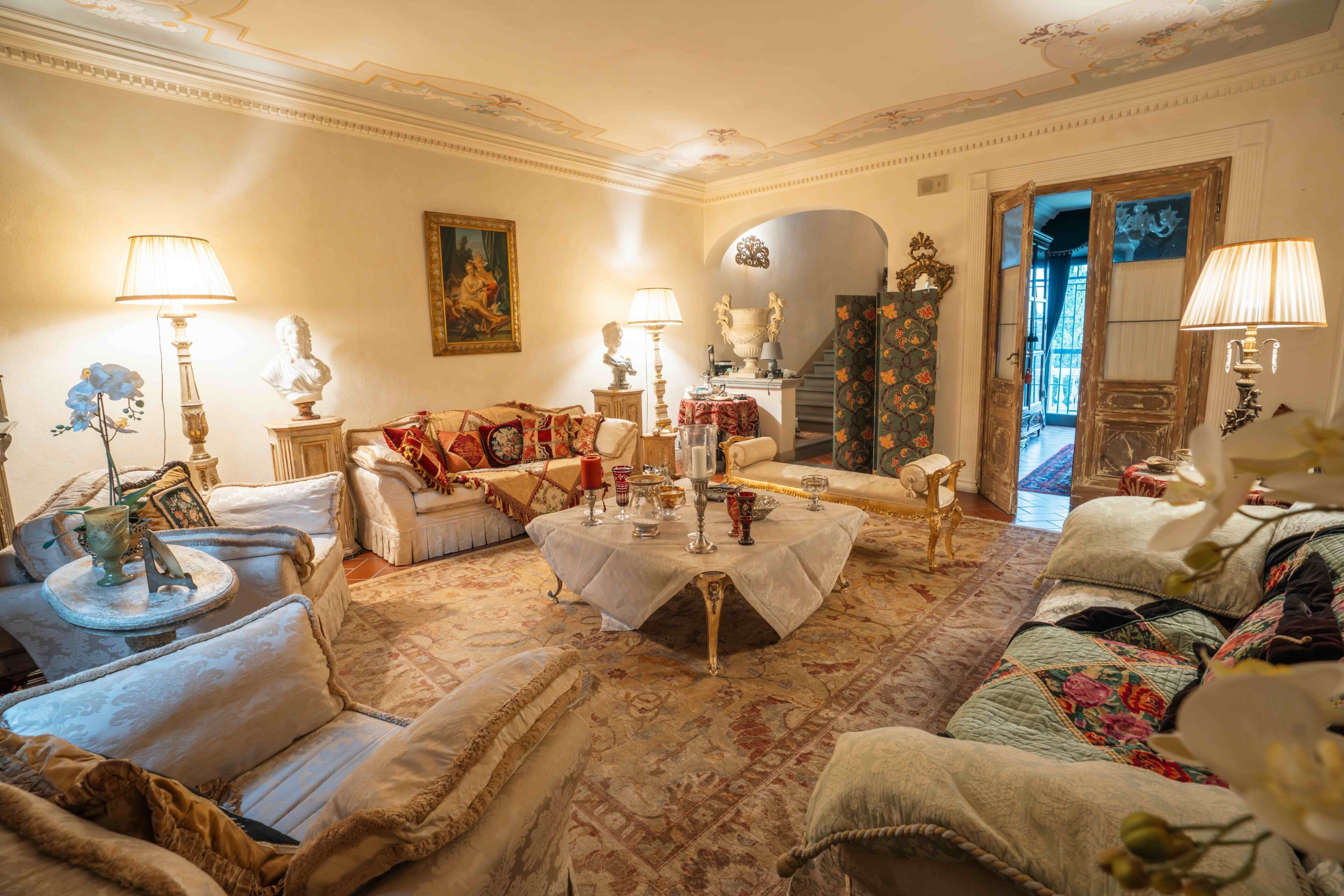 Una camera tradizionale con divano, un tavolo rotondo con candele e una scala che conduce a un'altra stanza.