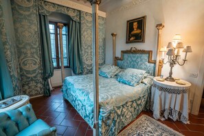 Une chambre à coucher avec un lit à baldaquin, un lustre et un portrait accroché au mur.