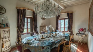 Uma sala de jantar com lustre, mesa ornamentada e decoração antiga.