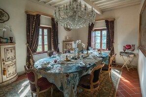 Een eetkamer met een kroonluchter, een versierd tafereel en retro decoratie.