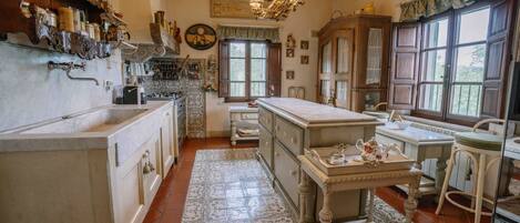 A traditional kitchen with wooden cabinets, a marble countertop, and a large island with a sink.