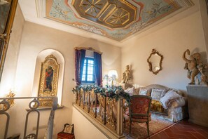 Een statige kamer met een trap, decoratieve versieringen, een bank en een beeldhouwkunstwerk.