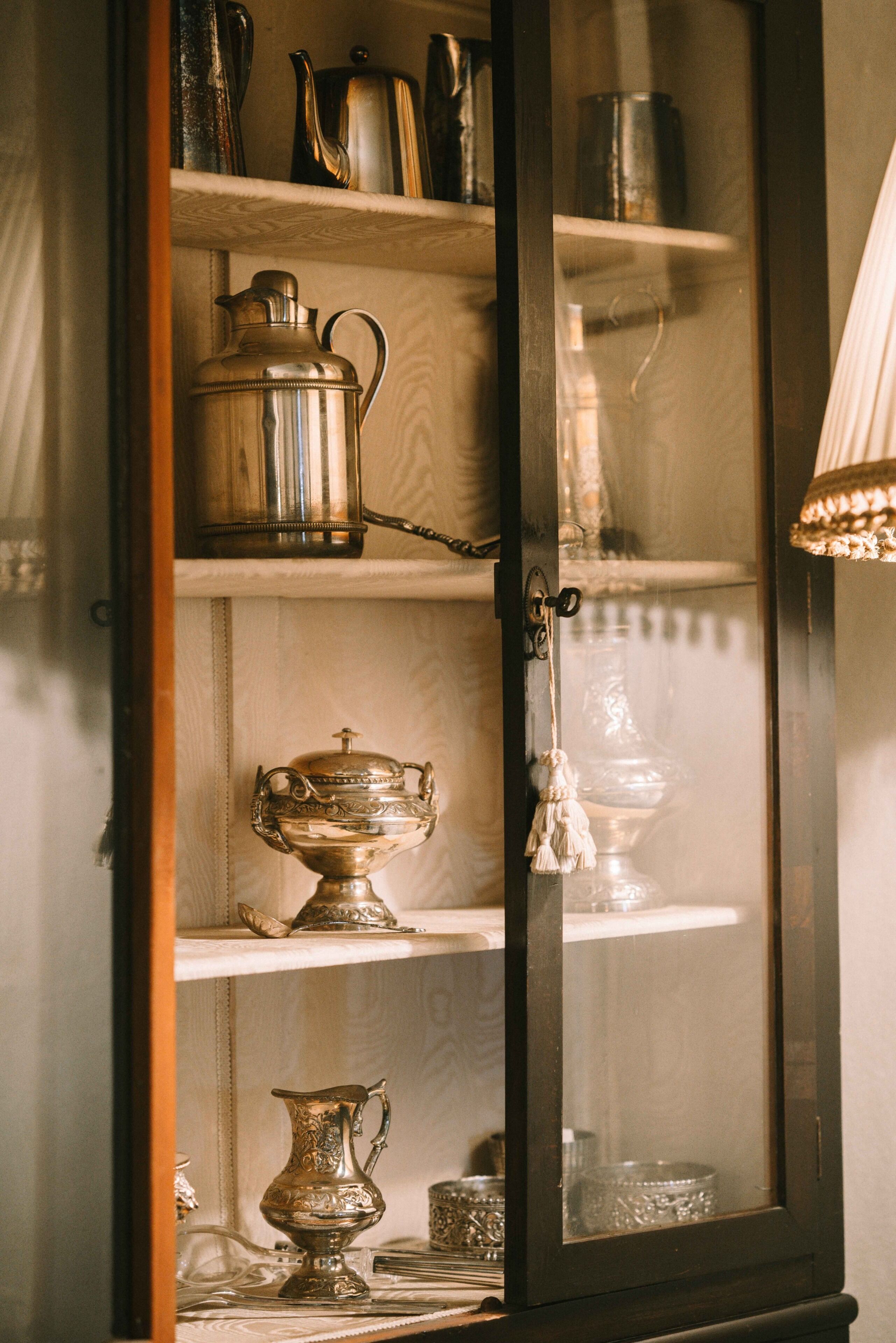 Eine gläserne Vitrine mit Regalen, die verschiedene Metallküchenutensilien beherbergt.