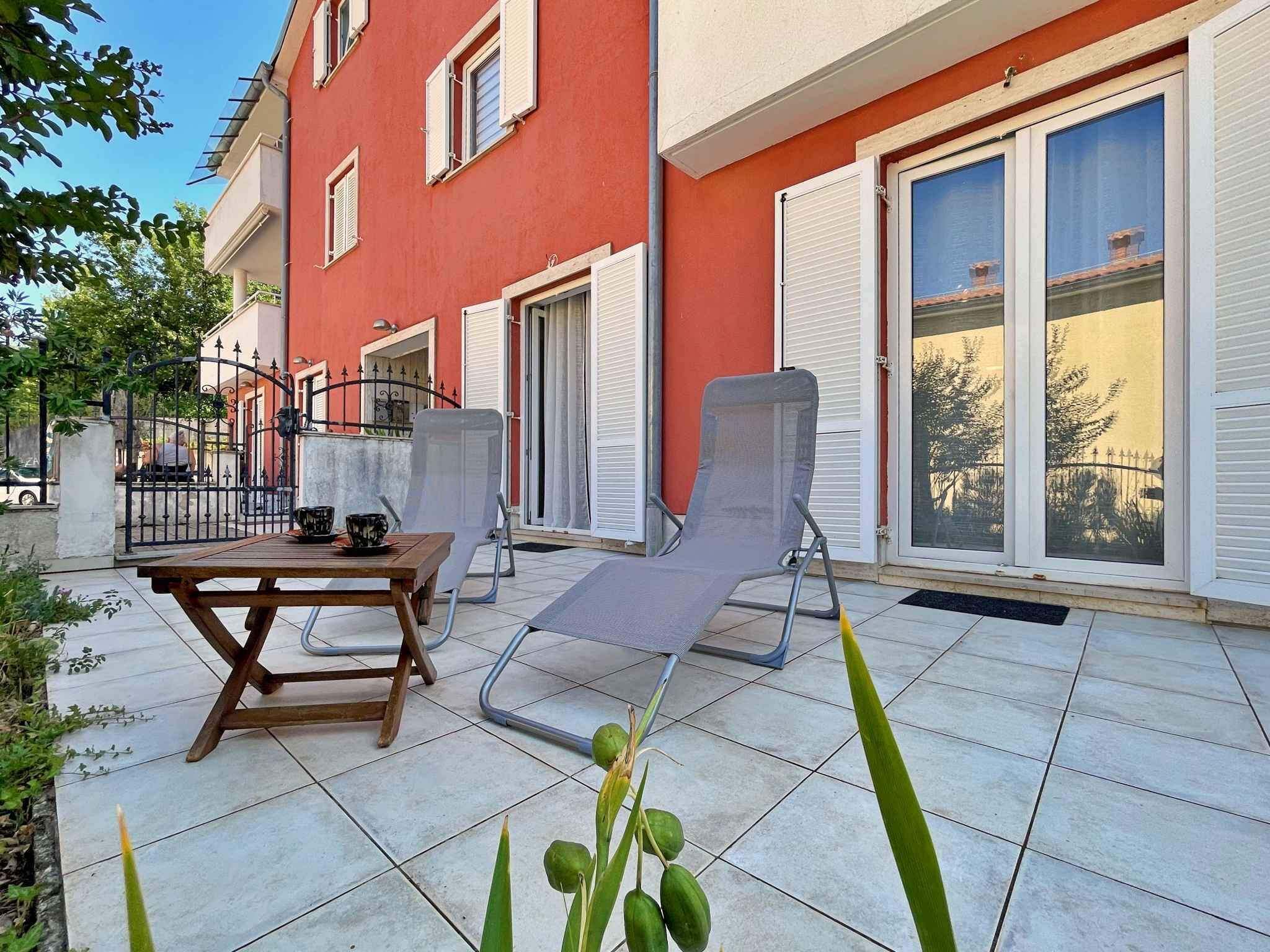 Un patio con tavolo e sedie, una porta scorrevole in vetro e una facciata di un edificio rosso.