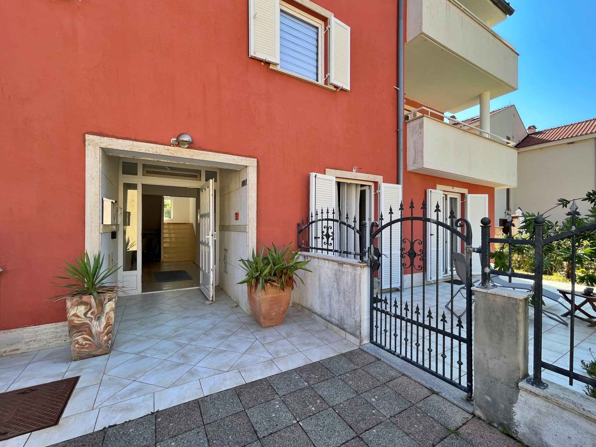 A red building with a gated entrance, potted plants, and a tiled patio area.