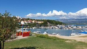 Un puerto deportivo con barcos amarrados, cielo despejado y edificios al fondo.