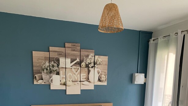 Un dormitorio con una cama grande, una obra de arte en la pared, una mesita de noche y una ventana con cortinas.