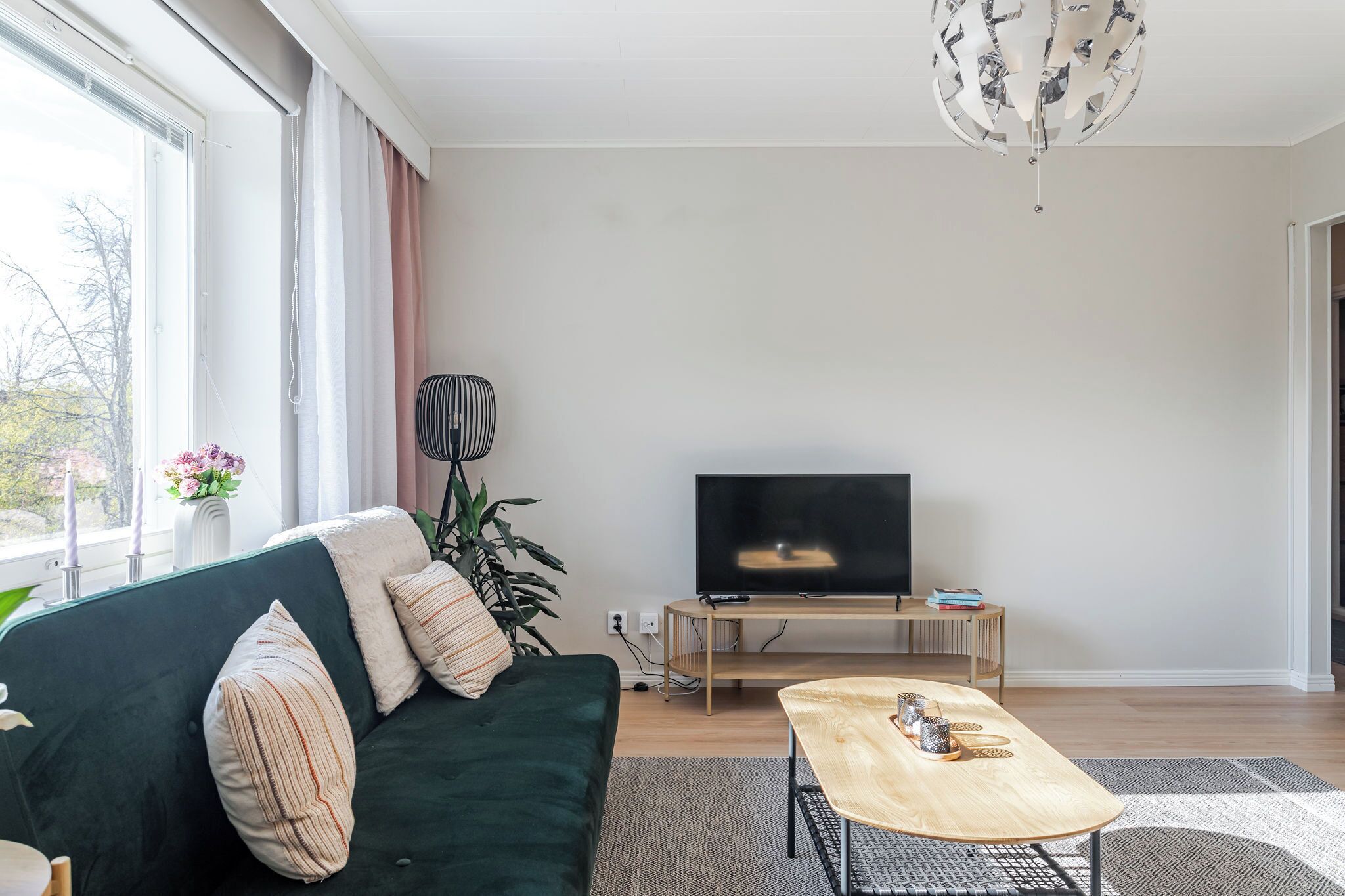 Una sala de estar moderna con un sofá verde oscuro, una mesa de centro de madera y un televisor de pantalla plana sobre un mueble de madera.