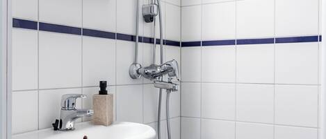 A modern bathroom with a white sink, a shower, and a mirror.
