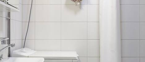 A bathroom with a white sink, a mirror, a towel rack with a striped towel, and a shower curtain.