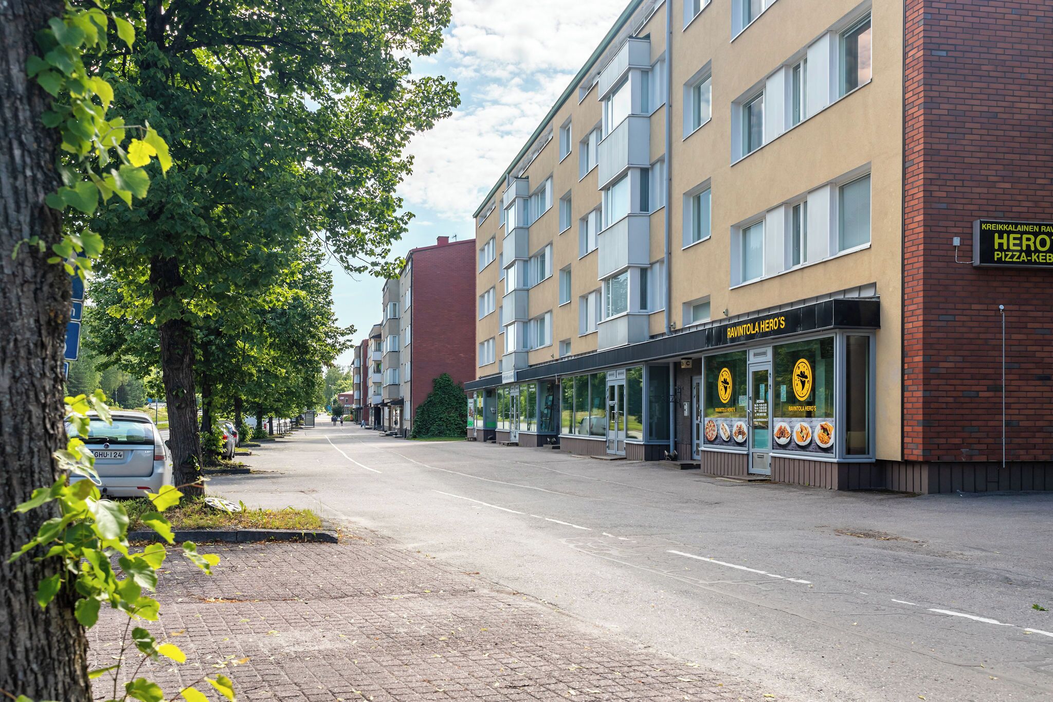 A street view with a building featuring a pizza restaurant named "Hero's Pizza-Kebab."