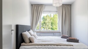A bedroom with a bed, curtains, a window, and a radiator.