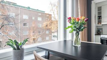A modern kitchen with a dining table, a potted plant, and a vase with flowers.