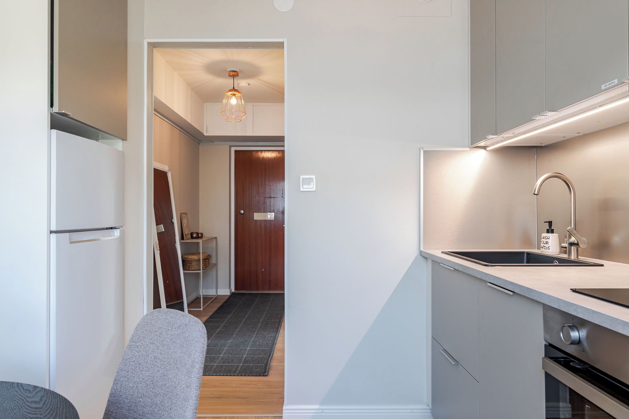 A modern kitchen with a built-in sink, stainless steel appliances, and a pendant light.
