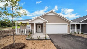 A two-story house with a garage, a front porch, and a landscaped front yard. - Traverse City Flats (Williamsburg)