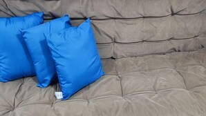 Een beige bank met twee blauwe kussens.