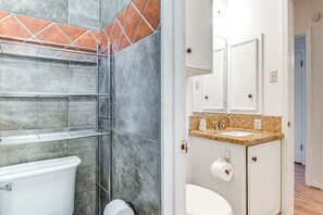 Un baño con ducha, inodoro, lavamanos y armario.